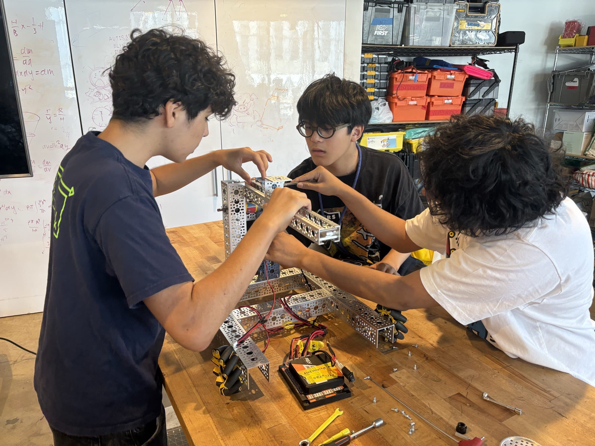 Students assembling a mecanum-wheel robot chassis at a NYC FIRST workshop